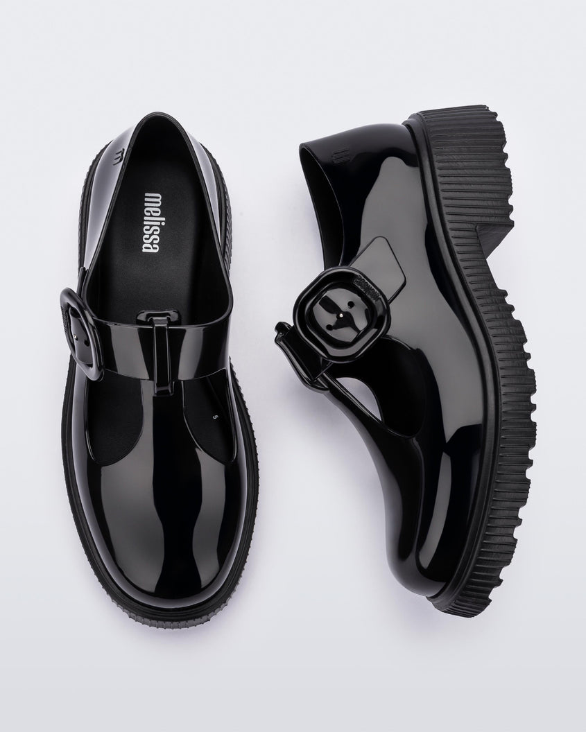 Top and side view of a pair of black Melissa Jackie loafers with two cut outs and a buckle detail strap.