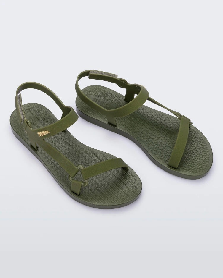 Angled top view of a pair of green metallic Melissa Sun Downtown sandals with a front and ankle strap joined together by a vertical strap and a triangle buckle.