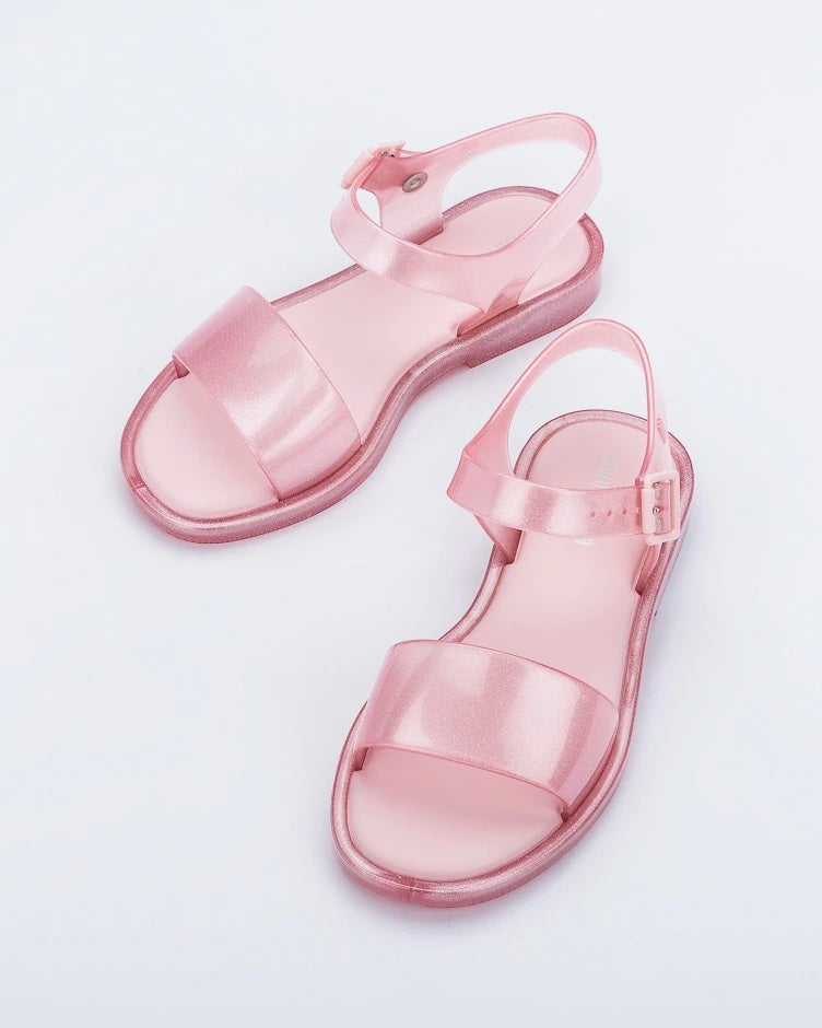 Angled view of a pair of pink glitter Mini Melissa Mar Sandals.