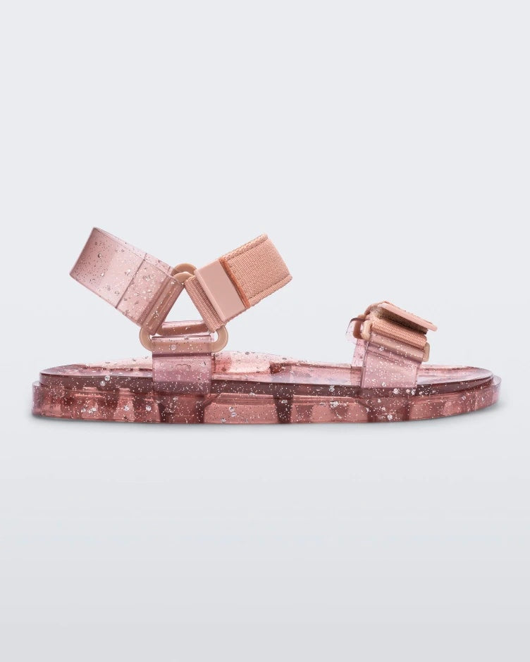 Side view of a Melissa Wide Papete sandal with transparent pink glitter sole with pink velcro straps