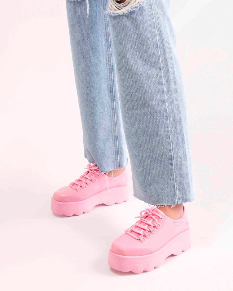 A model's legs wearing jeans and a pair of solid pink platform Melissa Kick Off Sneaker with laces.
