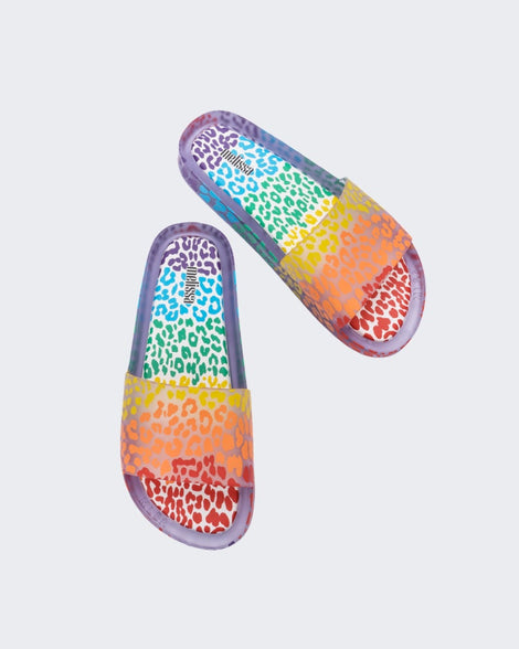 Top view of a pair of clear / orange Melissa Rainbow Beach slides with a clear base and a rainbow cheetah print pattern.