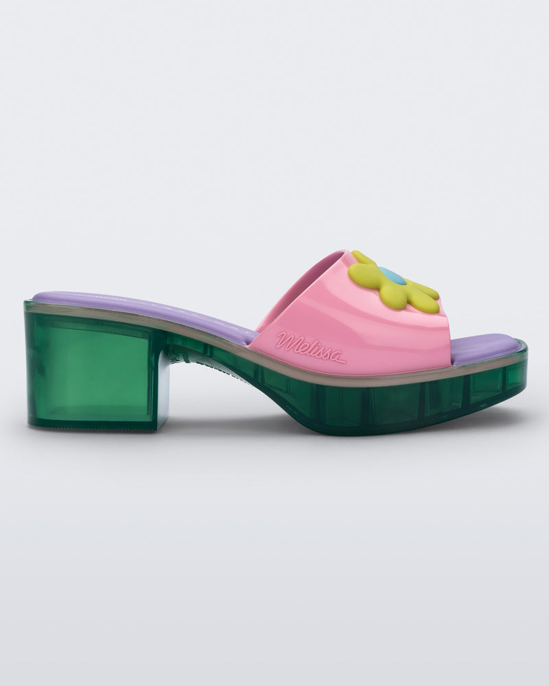 Side view of a Melissa Shape slide with green platform heel, a pink wide front strap with a yellow and blue flower on the top of the strap and a purple insole