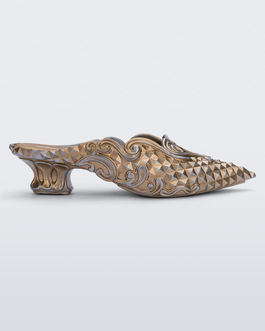 Side view of a Melissa Court mule with gold and silver coloring, a kitten heel and diamond- like pattern.