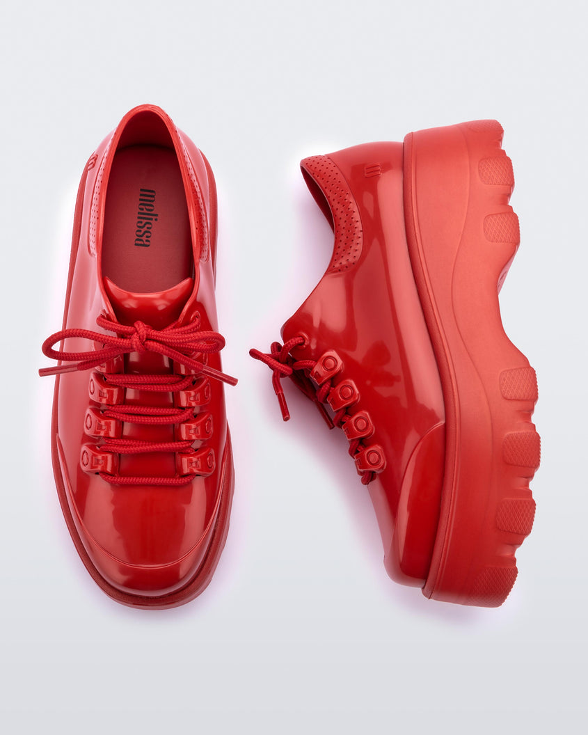 Top and side view of a pair of Melissa Kick Off sneakers in red with platform sole and red shoe laces