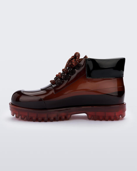 An inner side view of a pair of brown / black Melissa Ares combat boots with a translucent brown/black base, brown patterned laces, black top back and translucent brown sole.
