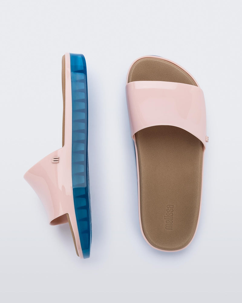 Top and side view of a pair of pink Melissa Beach slides with blue soles.