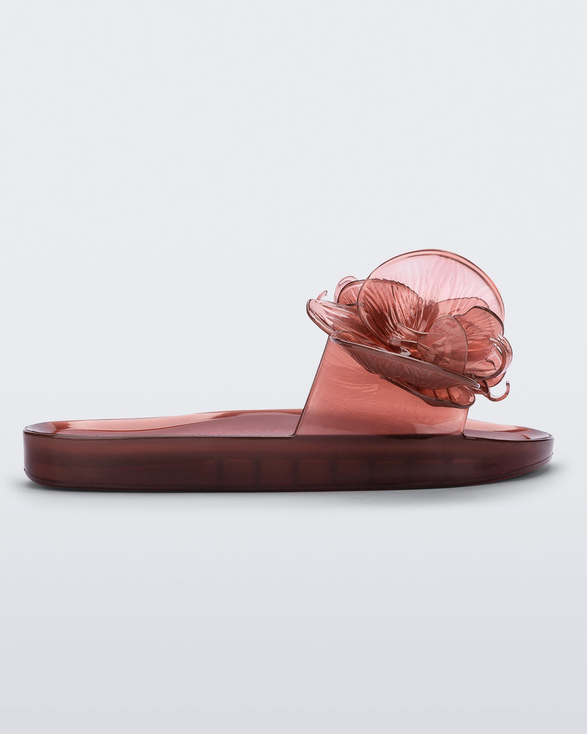 Side view of a red Melissa Flower Beach slide with flowers on the top.