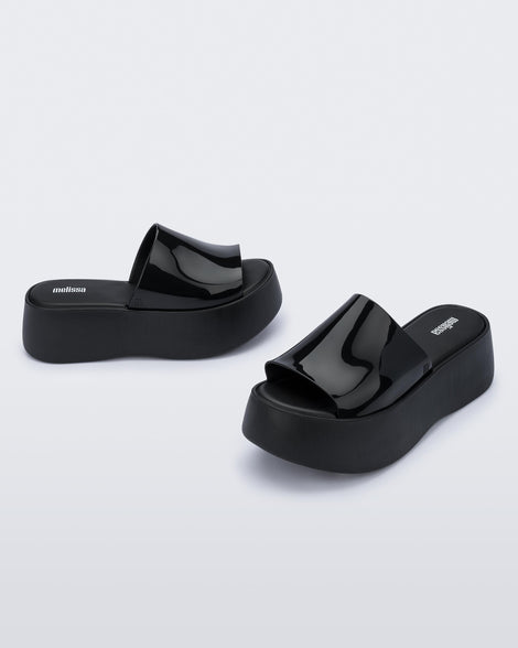 Angled view of a pair of black Melissa Becky platform slides.