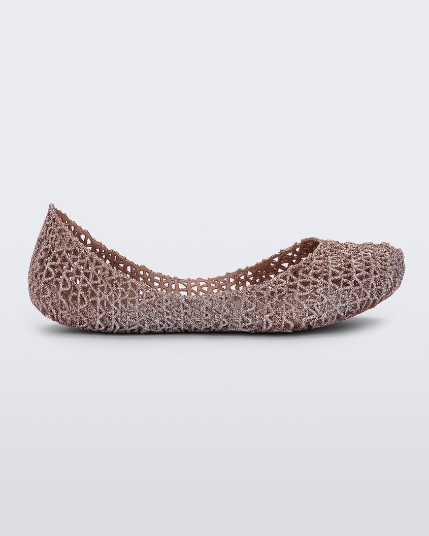 An outter side view of a pink metallic Mini Melissa Campana flat with a woven design base.