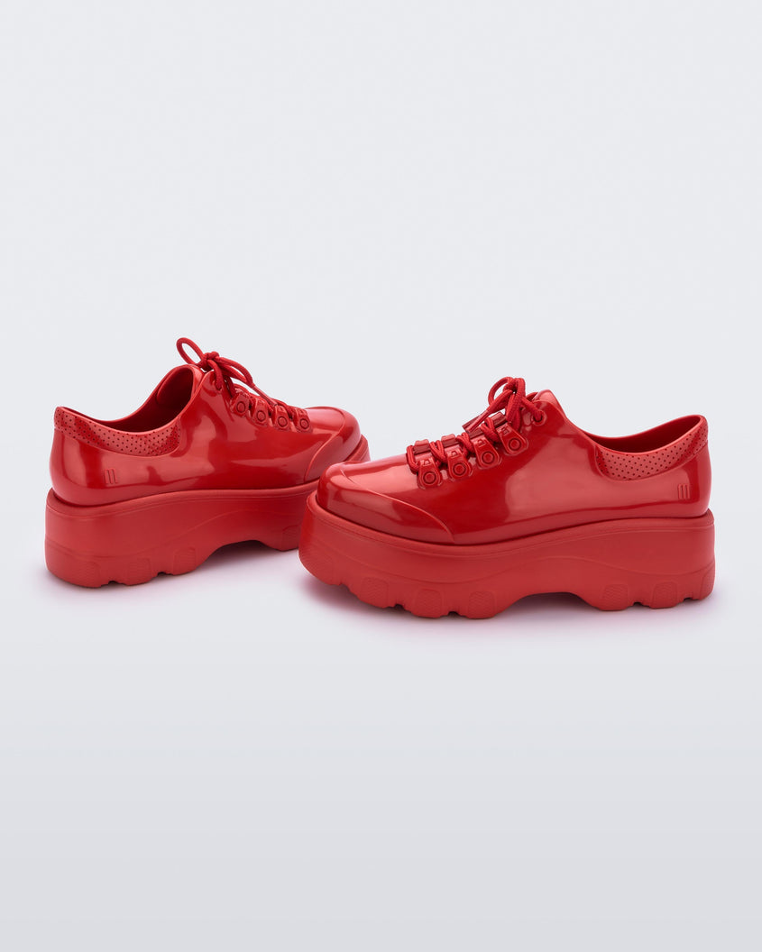 Angled view of a pair of Melissa Kick Off sneakers in red with platform sole and red shoe laces
