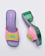 Top and side view of a pair of Melissa Shape slides with green platform heel, a pink wide front strap with a yellow and blue flower on the top of the strap and a purple insole