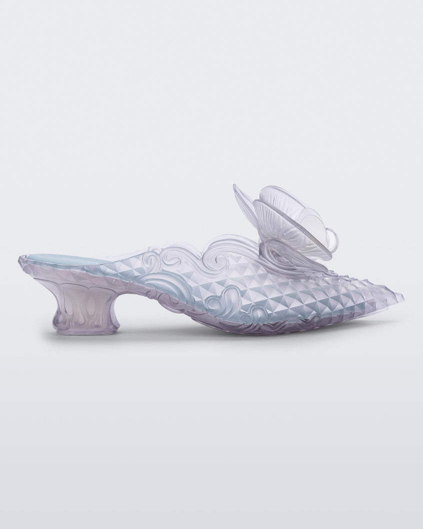SIde view of a Melissa Flower Court mule in clear with kitten heel and a 3D flower above the toe
