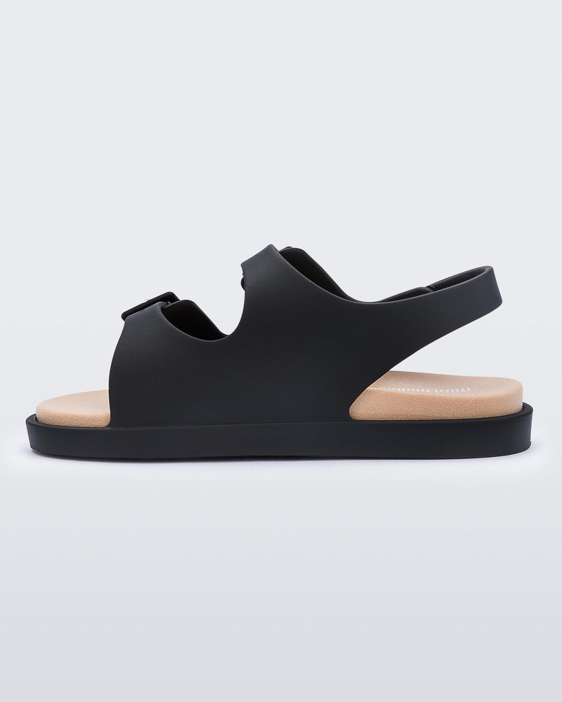 An inner side view of a black/beige Mini Melissa Wide Sandal with a black base, two black buckles at the top and a beige insole.