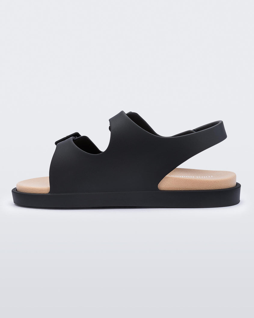 An inner side view of a black/beige Mini Melissa Wide Sandal with a black base, two black buckles at the top and a beige insole.