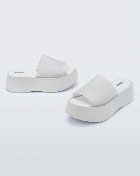 Angled view of a pair of white Melissa Becky platform slides.