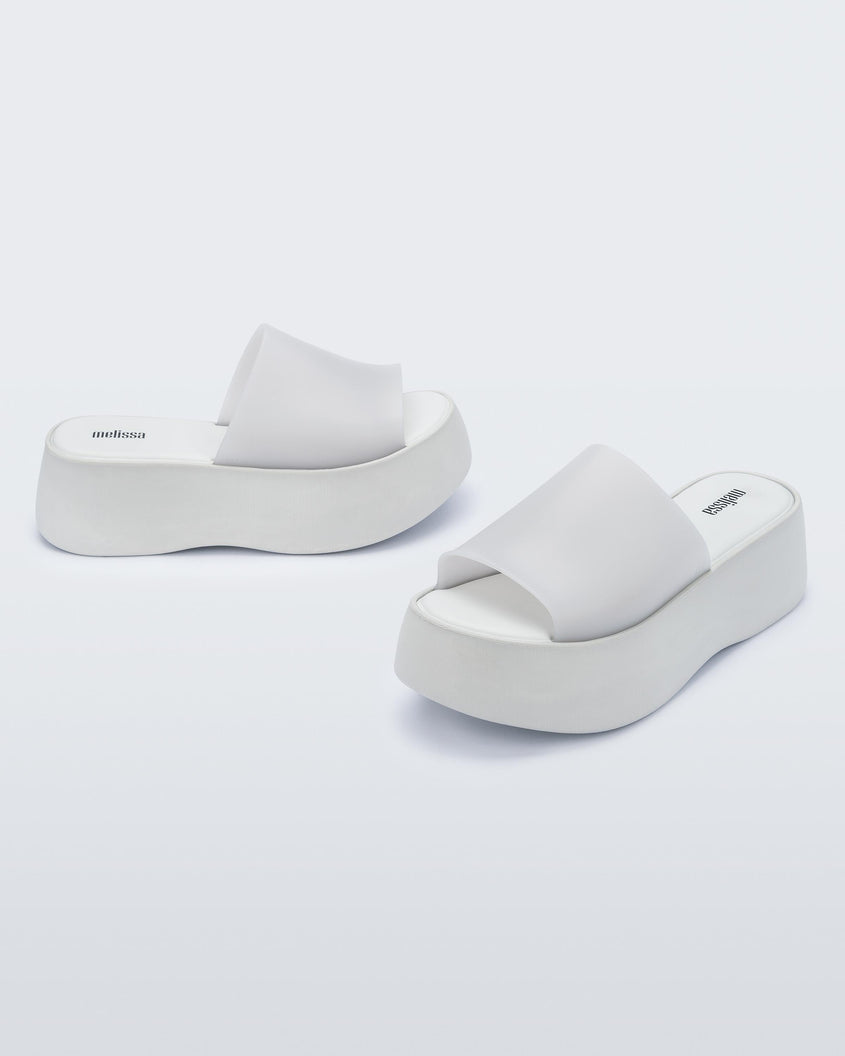 Angled view of a pair of white Melissa Becky platform slides.