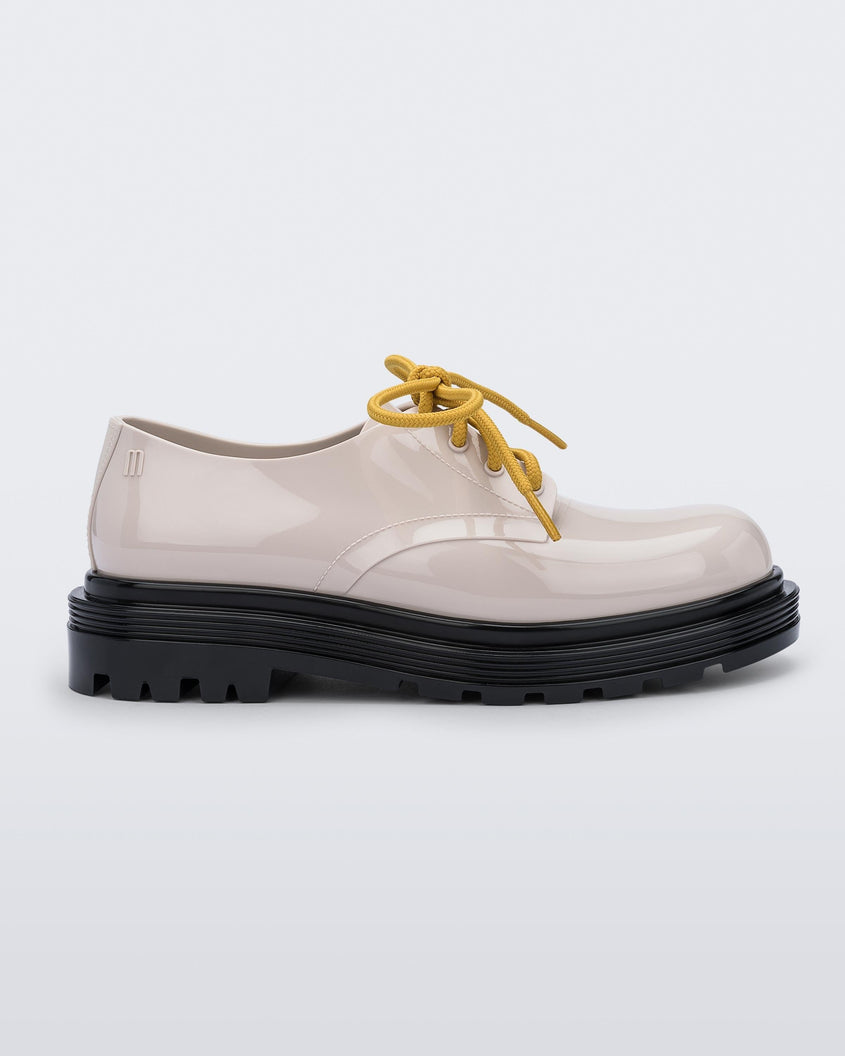 Side view of a pair of beige Melissa Bass sneaker with a beige base, yellow laces and a black sole.