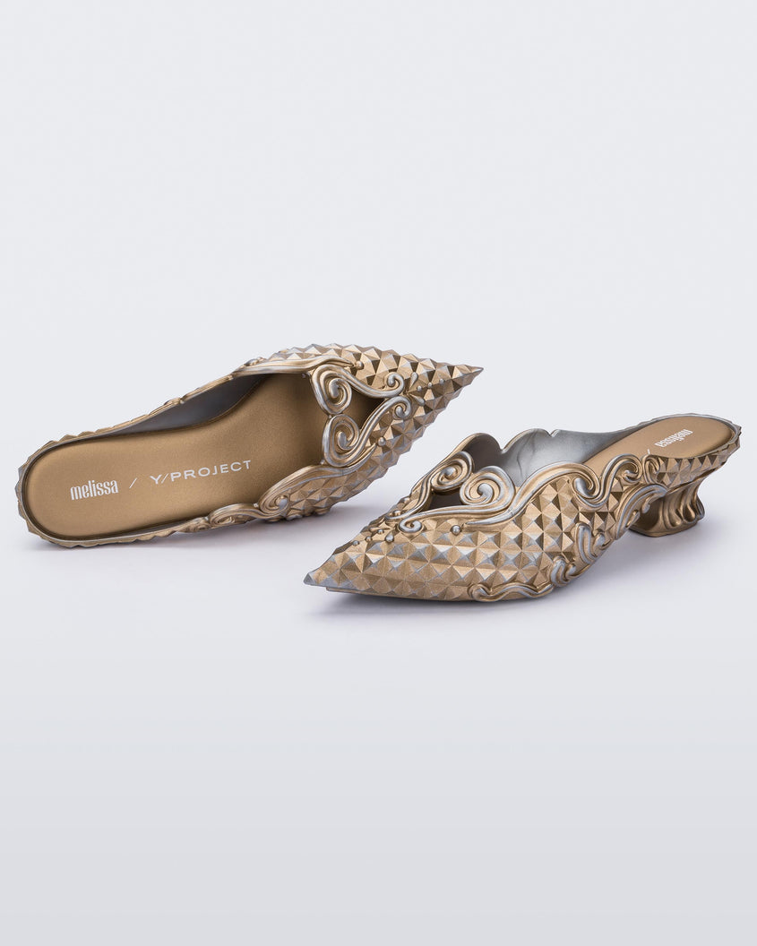Top and angled view of a Melissa Court mule with gold and silver coloring, a kitten heel and diamond- like pattern.