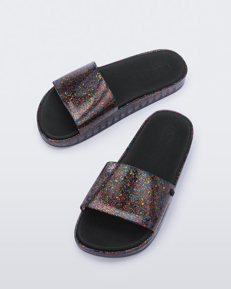 Angled view of a pair of clear/glitter Melissa Beach slides.