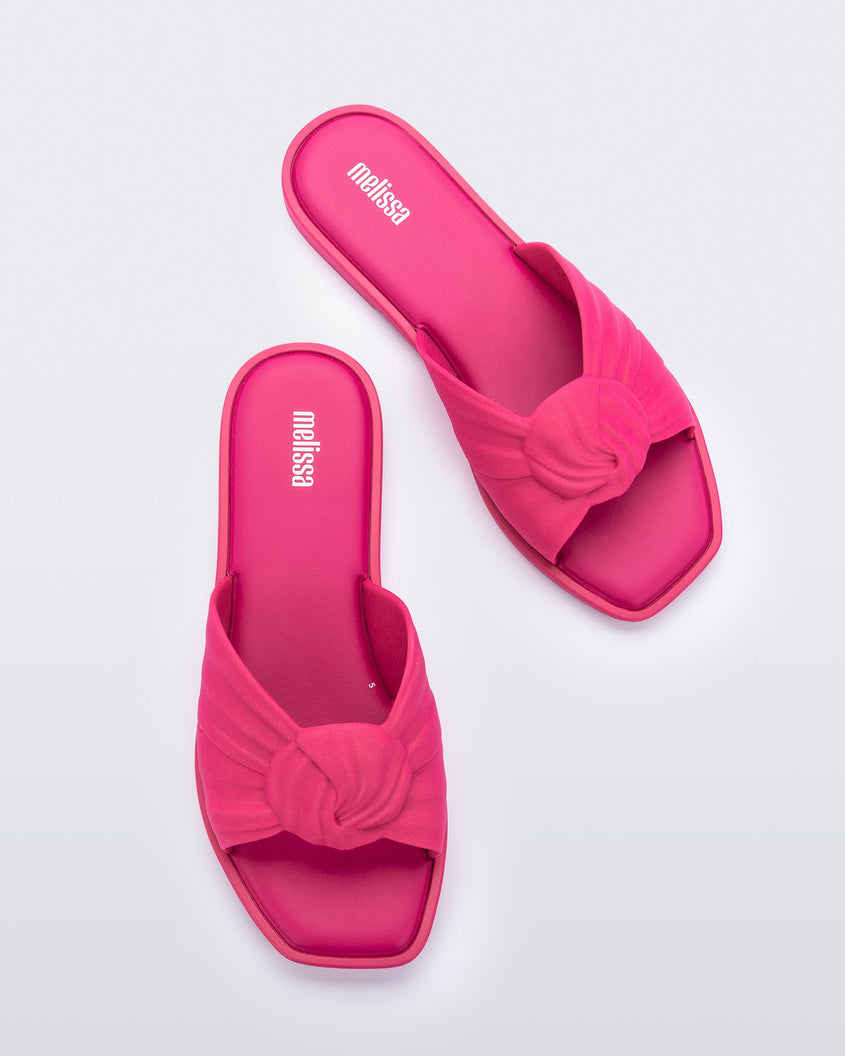 Top view of a pair of pink Melissa Plush slides with a twist front strap detail.