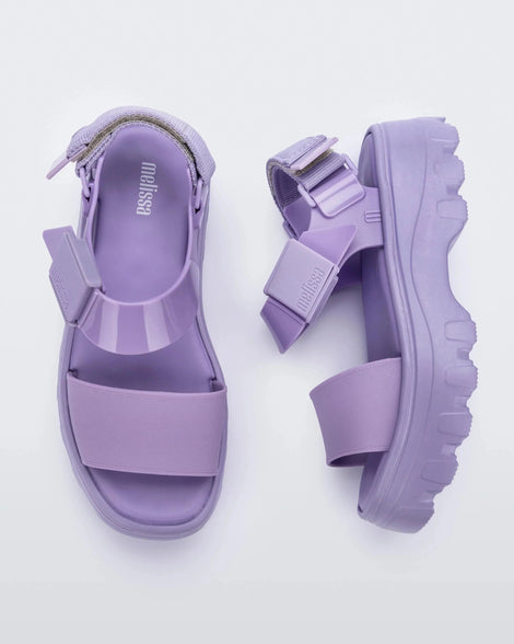 Top and side view of the Melissa Kick Off platform sandals in lilac. The sandal has an ankle strap with a plastic clasp closure on the front ankle side, additional velcro adjustable strap is on the back of the ankle strap.