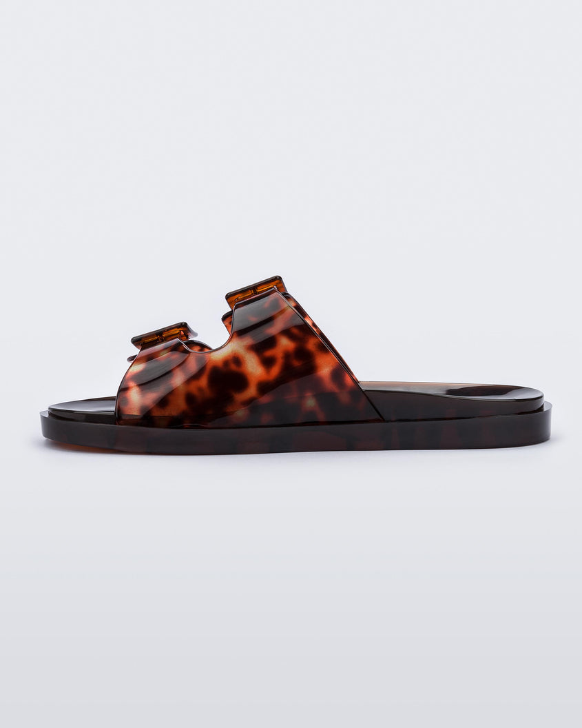 Inner side view of a Melissa Wide slide sandal with brown sole and brown tortoise colored straps