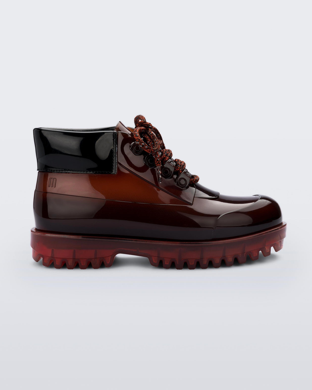 A side view of a brown / black Melissa Ares combat boot with a translucent brown/black base, brown patterned laces, black top back and translucent brown sole.