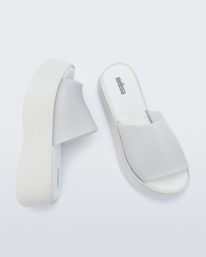 Top and angled view of a pair of white Melissa Becky platform slides.