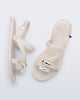 Top  and side view of a pair of beige Iris sandals with gold upper embellishments