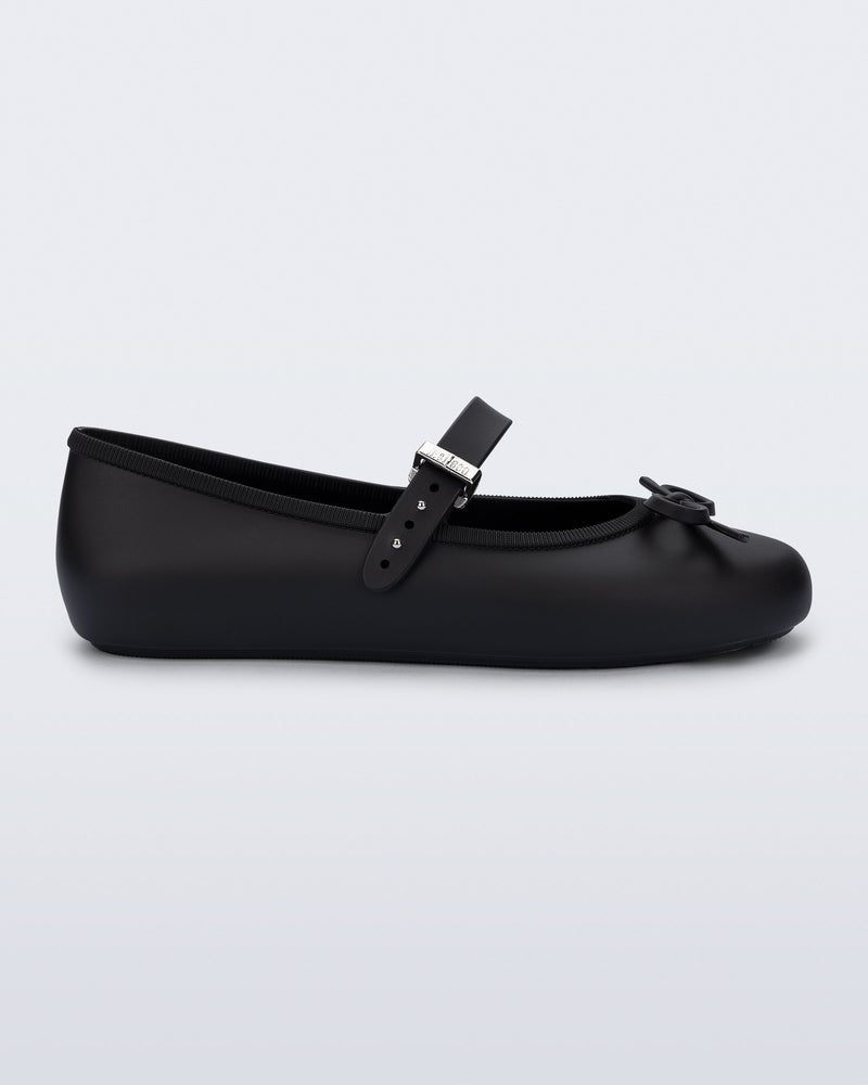 Side view of a black Soft Ballerina Delicate Bow flat with top strap and bow
