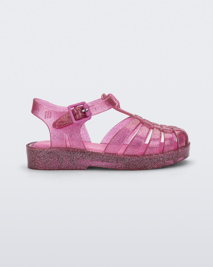 Side view of a Mini Melissa Possession baby sandal in glitter pink with velcro buckle closure on the ankle strap