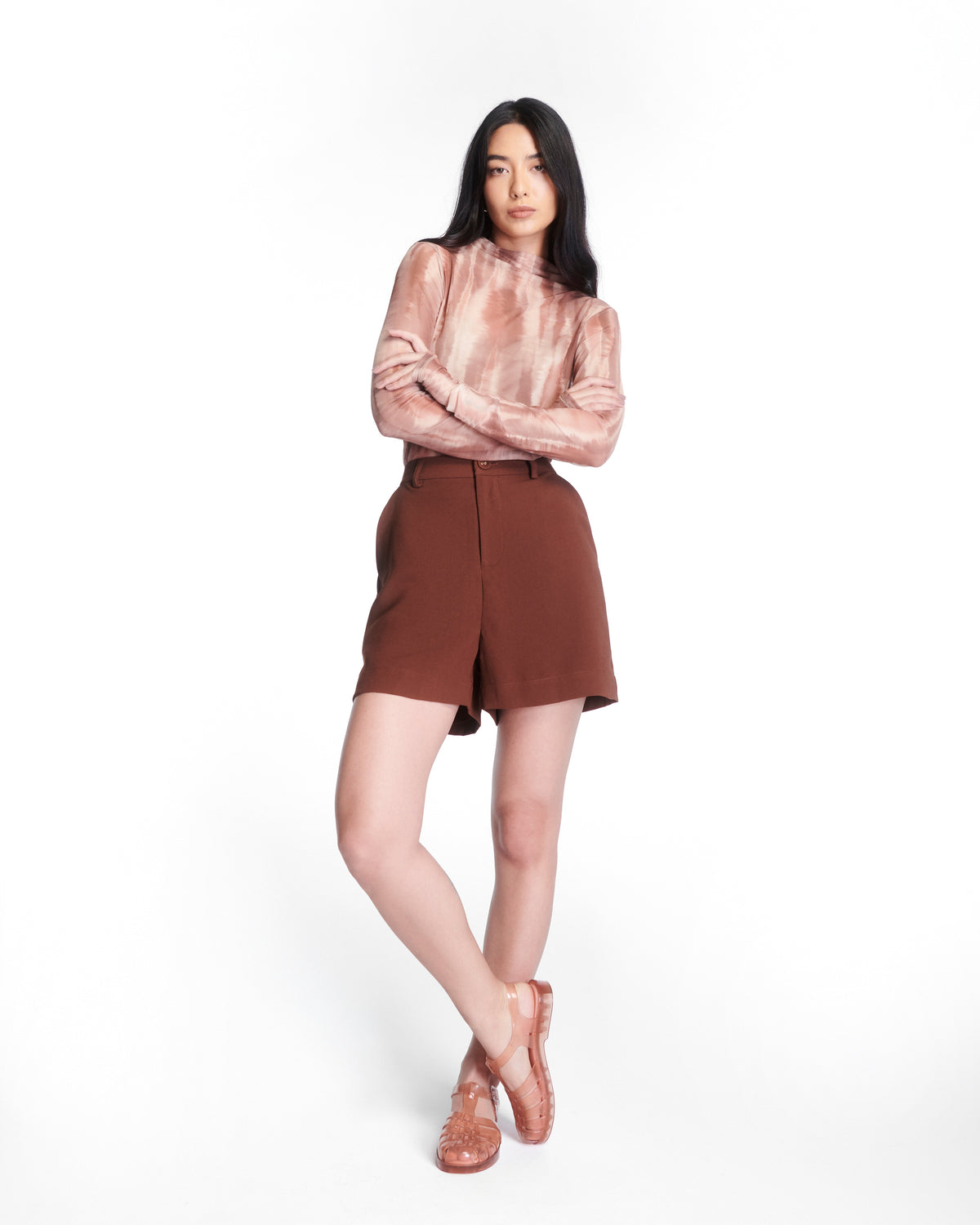 Model in brown shorts wearing a pair of clear peach Possession fisherman sandals