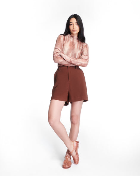 Model in brown shorts wearing a pair of clear peach Possession fisherman sandals