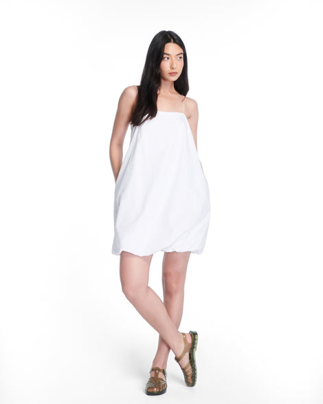 Model in a white dress wearing a pair of clear dark green Possession fisherman sandals