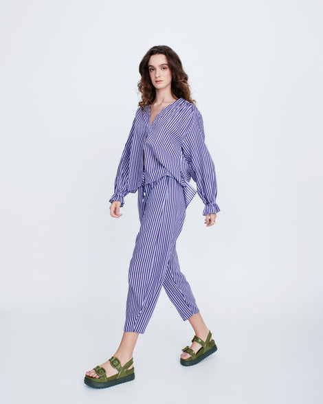 Model in a blue stripped pant set wearing a pair of green Cozy Sandal Platforms with dark green soles