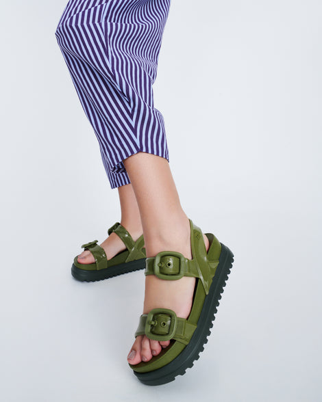Model's legs wearing a pair of green Cozy Sandal Platforms with dark green soles