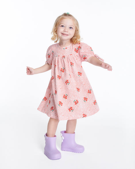 Child model in a red with flowers dress wearing a pair of lilac Welly Bloomy boots with white daisy on back