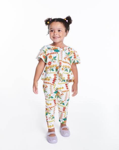 Child model in a pant set wearing a pair of pearly blue Pollen baby flats