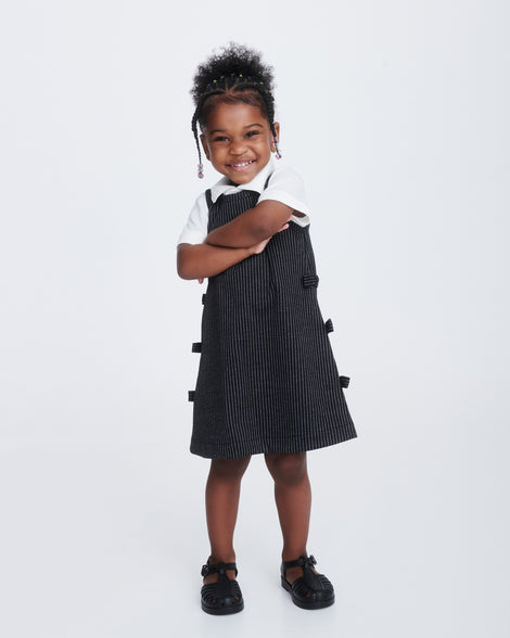 Child model in a black dress wearing a pair of black Aranha 79 baby flats with buckle