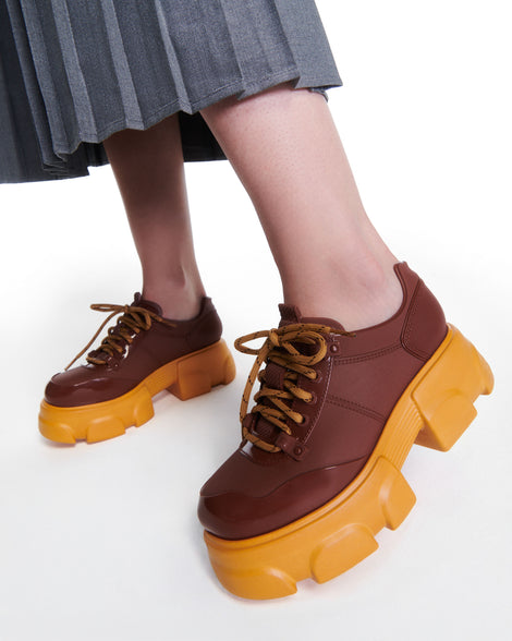 Model's legs wearing a pair of brown Camp platform Sneakers with yellow laces and sole