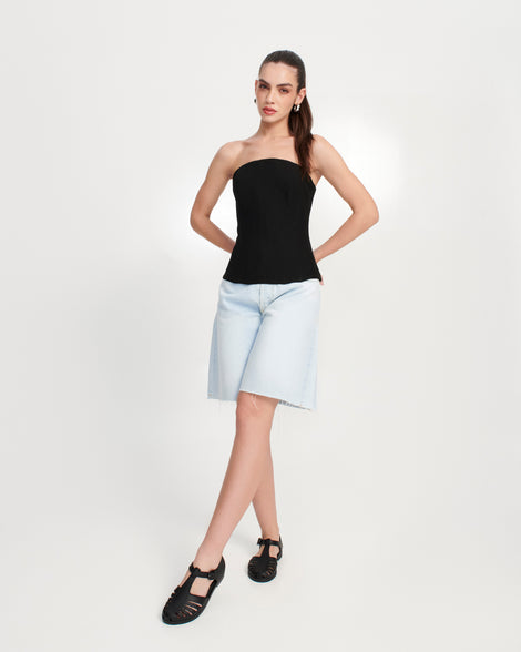 Model in jean shorts and black top wearing a pair of black Aranha 79 flats with buckle
