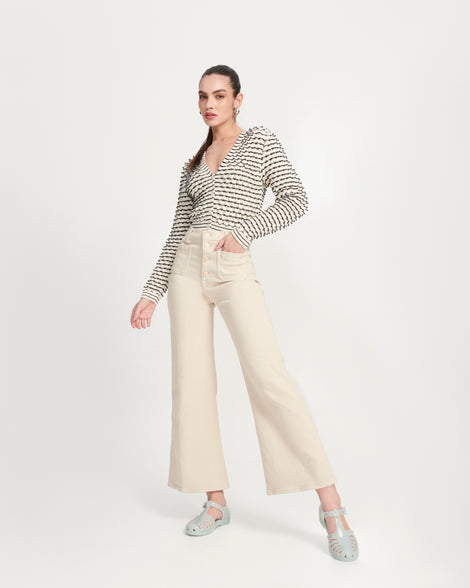 Model in beige pants and a sweater wearing a pair of milky green Aranha 79 flats with buckle