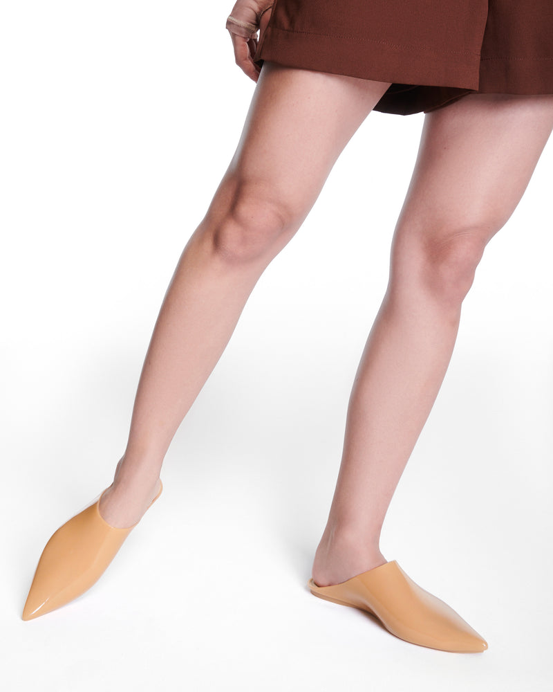 Model's legs wearing a pair of milky beige She slip ons with pointed toe