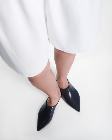Model's legs wearing a pair of grey She slip ons with pointed toe