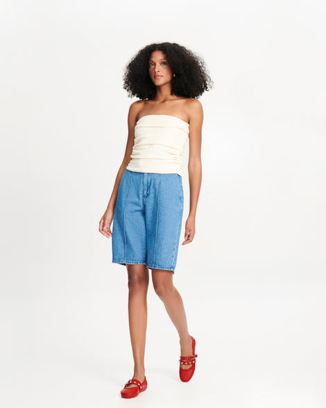 Model in a white top and long jean shorts wearing a pair of red Soft Ballerina Studs flats with silver embellishments