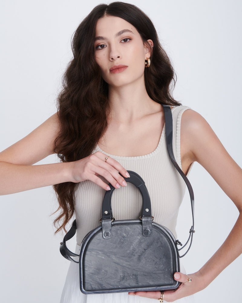 Model holding a grey Bowling bag with black handle strap and cross body strap