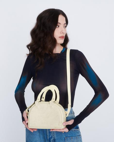 Model holding a beige Bowling bag with handle strap and cross body strap