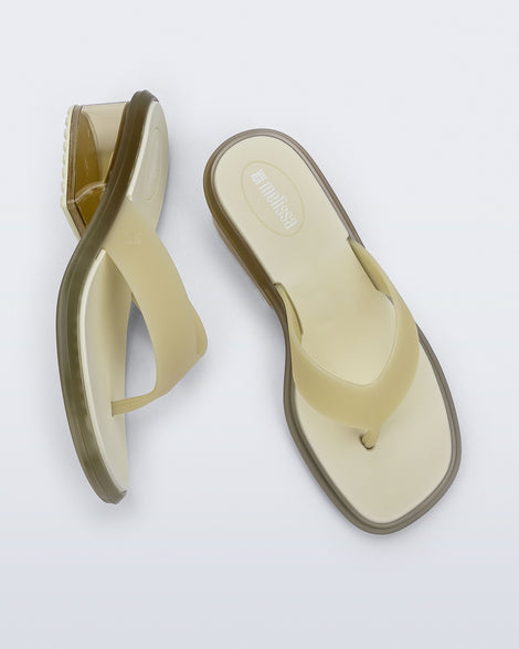 Top and side view of a pair of beige Margot flip flops with clear beige low heel 