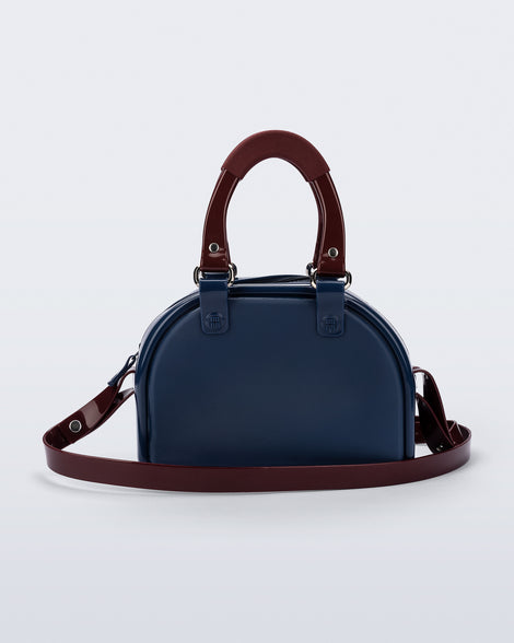 Back view of a blue Bowling bag with burgundy handle strap and cross body strap